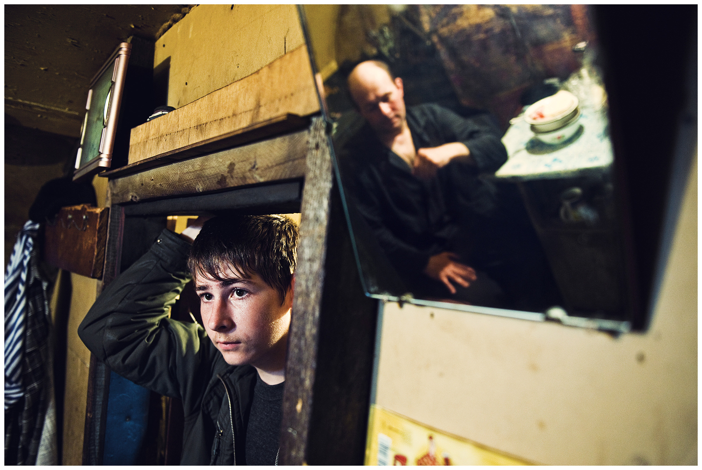 Shoyna village, Russia. A boy brings his father food to his workplace. The boy is reflected in a mirror.